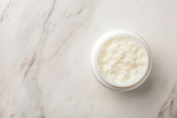 Jar of shea butter and space for text on marble background, top view