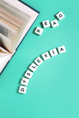 Dyslexia and read words with an open book on mint background, reading difficulty and disorder...