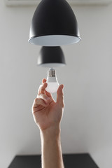 Changing the bulb for led bulb in floor lamp in black colour. On light gray background