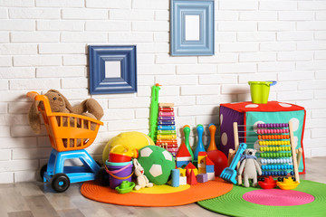 Different child toys on floor against brick wall