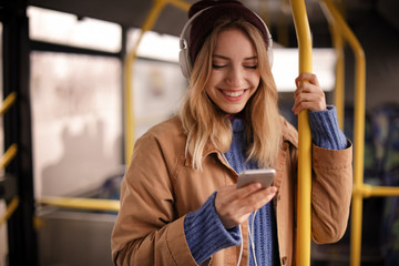 Young woman with headphones listening to music in public transport