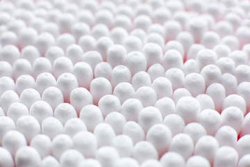 Closeup view from above on round pack of cotton buds on pink background