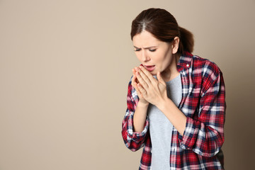 Woman suffering from cough on color background. Space for text