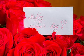 Close up of a beautiful bouquet of red roses with a happy mothers day card. Mother's Day concept.spring holidays and bouquet of roses. Elegance gift. Floral background.