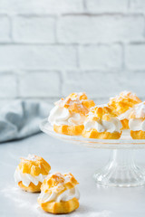 Delicious sweet profiteroles with cream on a modern kitchen table