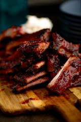 Smoked ribs ready to be eaten on wooden plate.​