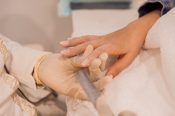 Obraz na płótnie Canvas manicurist does manicure to client in beauty salon with rubber gloves