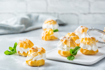 Delicious sweet profiteroles with cream on a modern kitchen table