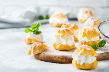 Delicious sweet profiteroles with cream on a modern kitchen table