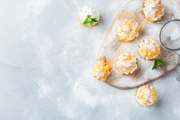 Fototapeta na wymiar Delicious sweet profiteroles with cream on a modern kitchen table