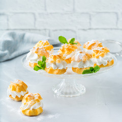 Delicious sweet profiteroles with cream on a modern kitchen table