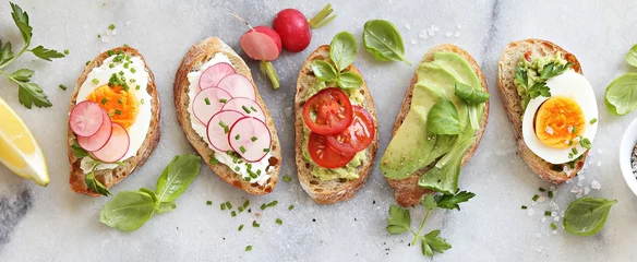 Poster Ontbijtsandwichbrood met avocado, ei, radijs en tomaten. Bruschetta of gezonde snackideeën © losangela