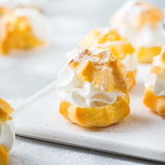 Delicious sweet profiteroles with cream on a modern kitchen table