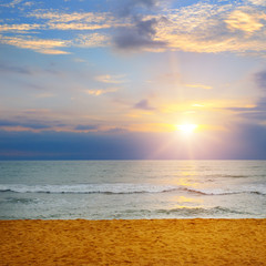 Beach of the ocean and bright sunrise .