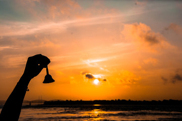 atardecer río Ganges en Varanasi, India. siluieta de mano tocando la campana, copy-space