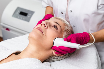 Beautiful senior woman having radio waves lifting face treatment.