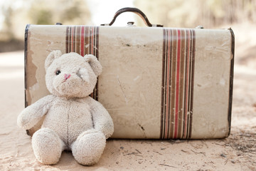 Ragged Teddybear and Old Suitcase on Dirt Road - Amber Alert