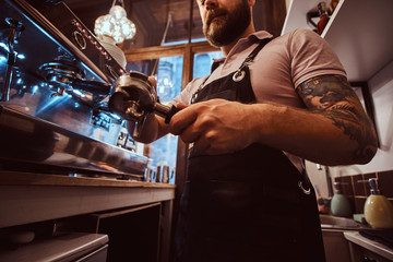 Low angle photo of a barista holding a portafilter, working in the coffee shop or restaurant