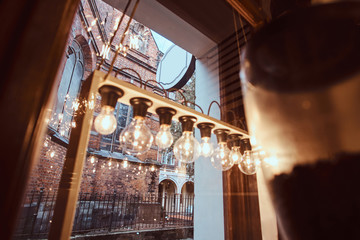 The interior of the coffee shop with overlooks the beautiful old building, showcase decorated with lamps and dishes, inside view