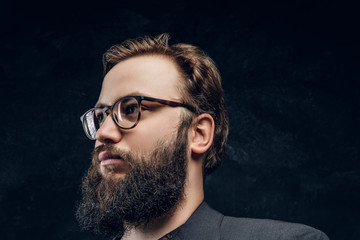 Close-up portrait of a smart bearded man in glasses in a dark studio