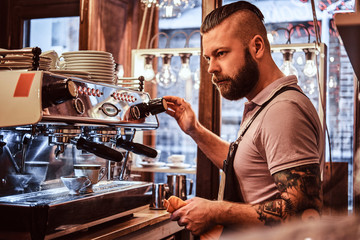 Handsome barista in uniform preparing a cup of coffee for a customer in the coffee shop