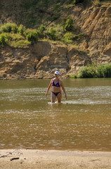 Girl in a lilac bathing suit out of the water on a sandy beach