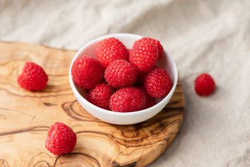 Fresh Raspberries In A Bowl On Wood and Linen Background