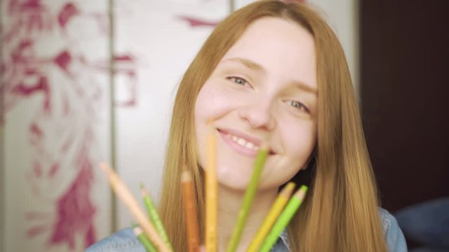 Close-up portrait of a beautiful excited woman drowing with pencils amd smiling 