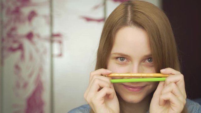 Close-up portrait of a beautiful excited woman drowing with pencils amd smiling 