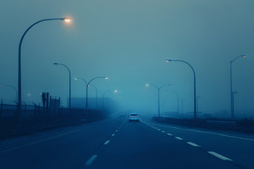Highway in mystic fog mist smog. Cars on freeway road at evening in american city country. Poor...