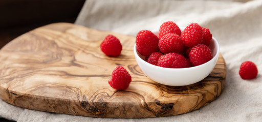 Fresh Raspberries In A Bowl On Wood and Linen Background