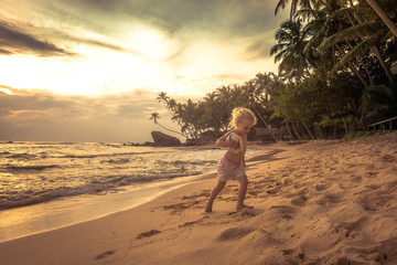 Cute child toddler walking on sunset beach during summer vacation concept happy childhood travel lifestyle 