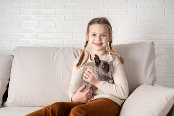 Portrait of happy girl with rabbit indoors