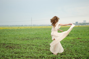 A young tall woman with a long hair at the green field