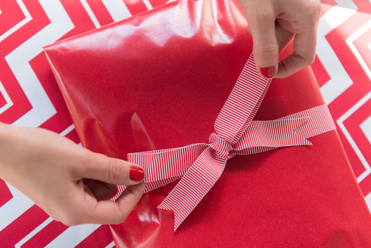 Hands of woman tying bow on Christmas present