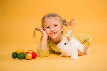 baby girl with Easter Bunny on yellow background.Easter little girl, kid holding bunny rabbit...