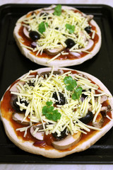 Two uncooked pizzas ready for the oven