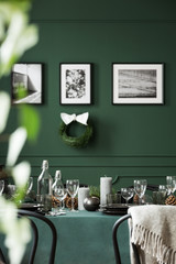 Christmas garland and black and white posters on green wall of dining room set for christmas dinner
