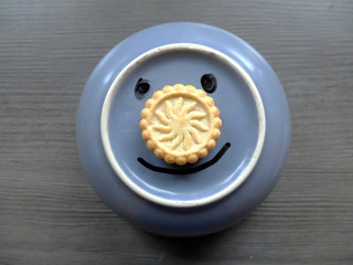 Funny face made of food (cookie) and bowl. Smiley expression.