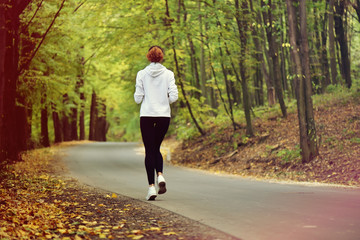 Running woman. Female runner jogging during outdoor workout in forest. Sport model outdoors....