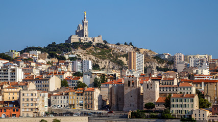 Obraz premium Panoramic cityscape of Marseille with the church Notre-Dame de la Garde, landmark of the city, on a hilltop. Marseille, Provence, France. Holidays in France.