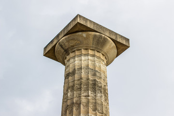 ancient Greece architecture single column object foreshortening from below on gray sky background, touristic site concept, copy space