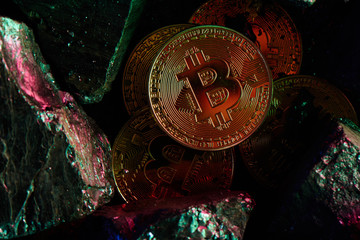 The concept of mining virtual currency. Bitcoins on a black coal background close up