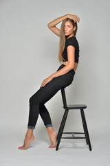 Fototapeta na wymiar Sexy beautiful woman in black sitting on high chair.