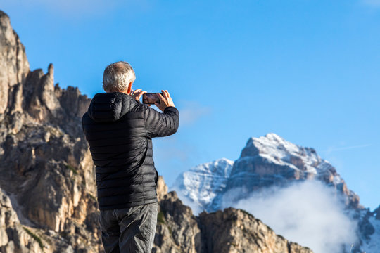 Man taking photograph with smartphone at Giau Pass in the Dolomites