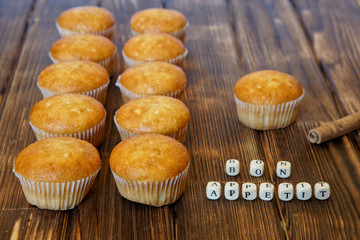 Golden cupcakes and cinnamon sticks lie on a wooden surface of pine planks. Bon appetite. Tasty and healthy food