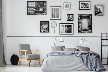 Elegant retro armchair next to king size bed with grey bedding in contemporary bedroom interior...