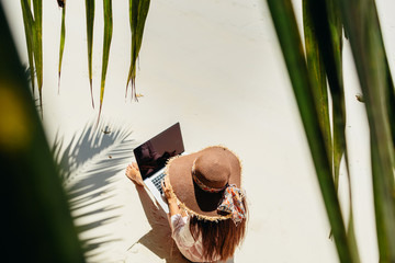 woman working remotely on laptop on beach in tropics - obrazy, fototapety, plakaty