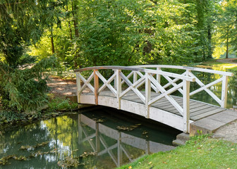 Small wooden bridge over a stream with trees in the background.