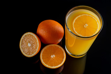  orange, orange juice in a glass on a black background